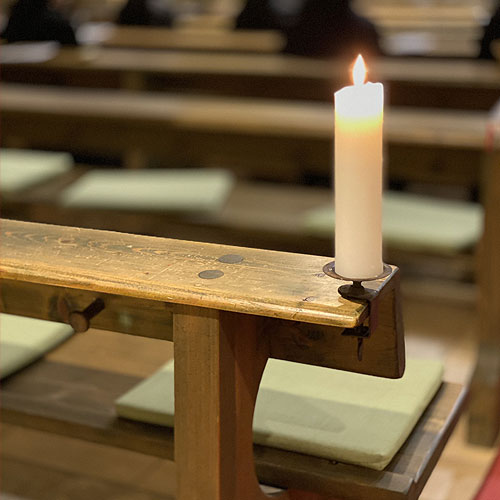 Eine große weiße Kerze brennt in einer Kirche