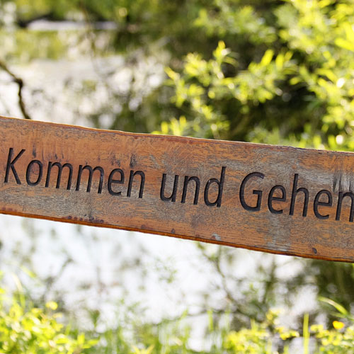 "Kommen und Gehen" steht auf einem Holzbalken